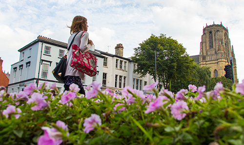 A woman walking next to flowers and the University