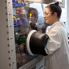 Researcher in white lab coat conducting experiment in machine