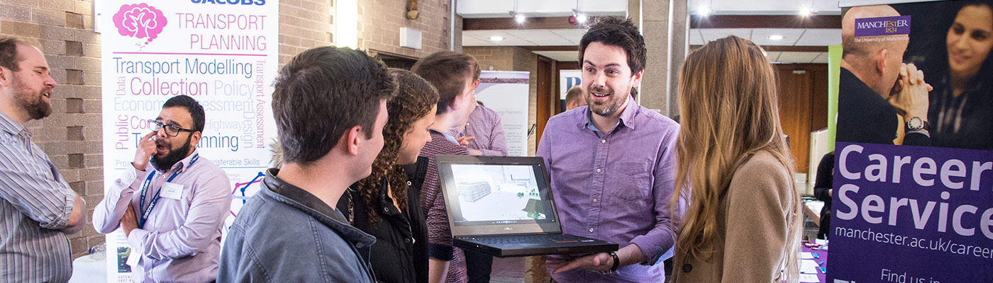 Recruiter holding laptop chatting to students at careers fair