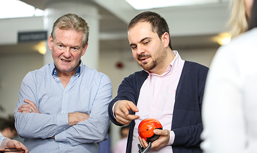 Visitor and master's student in discussion at trade show