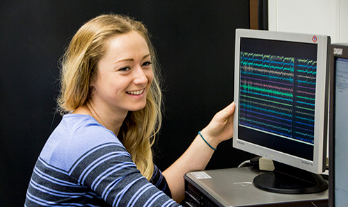 Student smiling next to computer monitor
