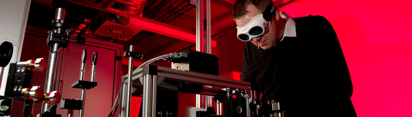 Researcher using laser equipment wearing dark safety goggles