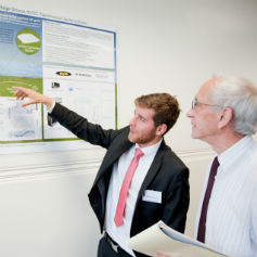 Two men looking at a chart on a wall