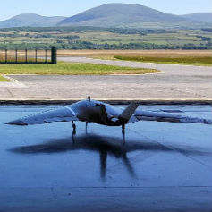 Military aeroplane in hangar looking out at fields and mountains
