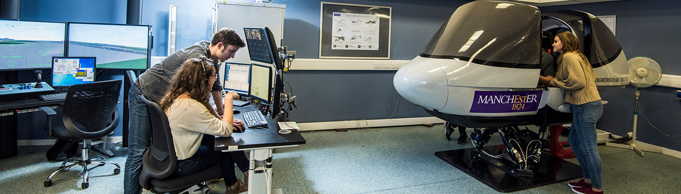 Two students on computer station while two others sit in flight simulator