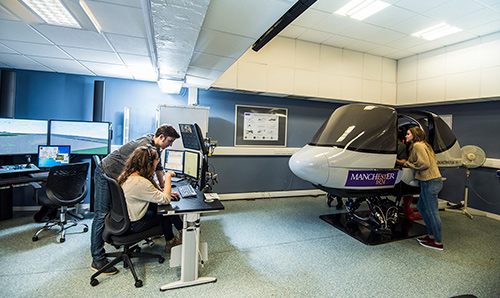 Two students on computer station while two others sit in flight simulator