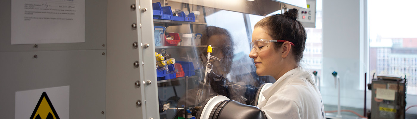 Researcher in white lab coat conducting experiment in machine