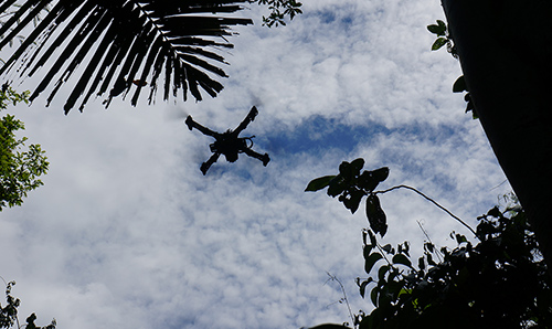 Drone silhouette in front of cloudy blue sky