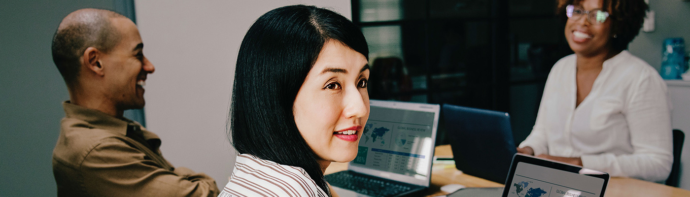 Men and women sat in an office smiling around computer screens