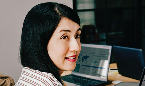 Men and women sat in an office smiling around computer screens