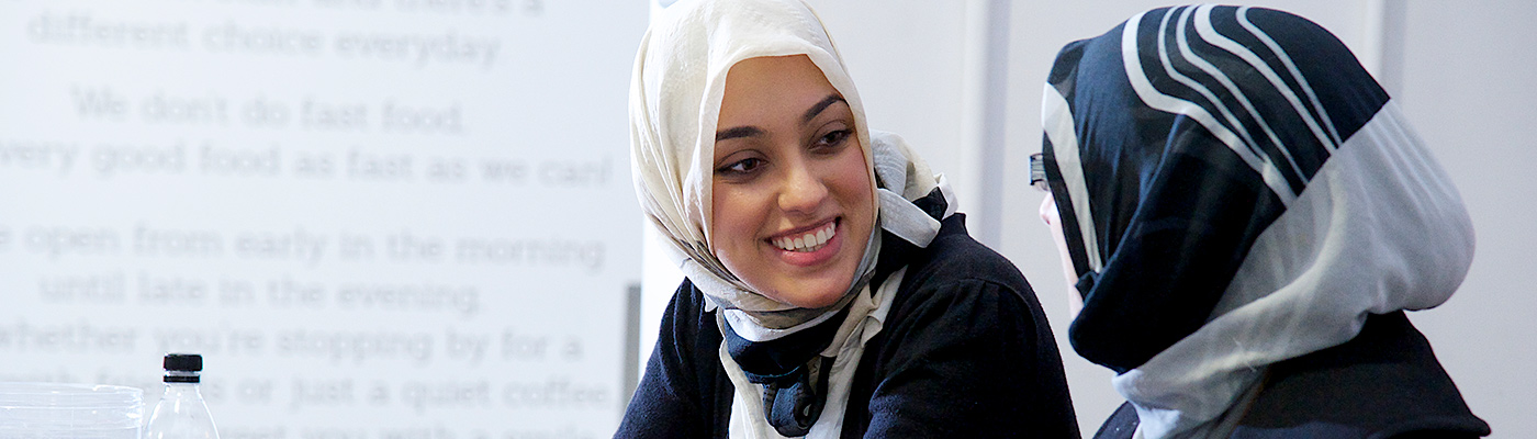 Two female students smiling while in discussion