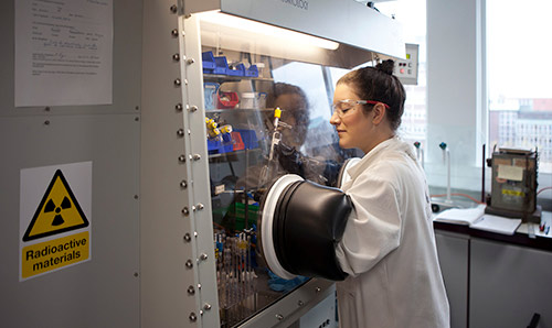 Researcher in white lab coat conducting experiment in machine