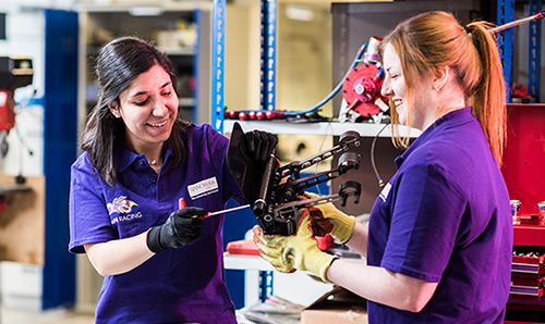 Students wearing gloves adjusting metal device