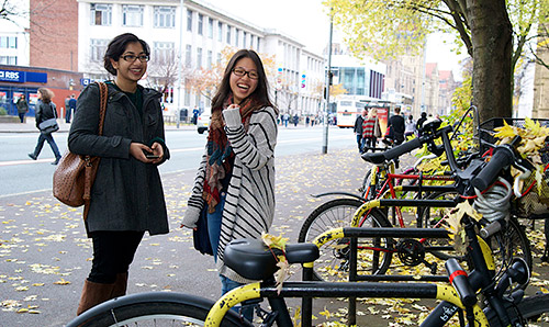 Two students laughing by bike stands